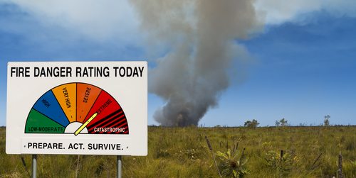 Fire danger rating board with smoke in the distance